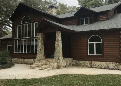 Luxury log cabin with brick beams, high ceilings, large windows, and a beautiful roof