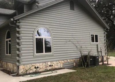 White painted log cablin with white bricks on the bottom