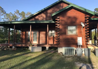 Brown log cabin with new green roofing, power installation, and air conditioning