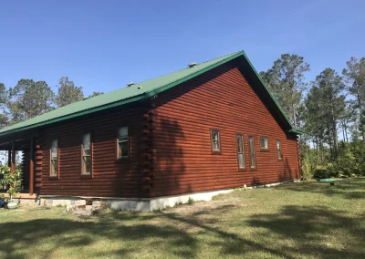 Square log cabin with thick green metal roof