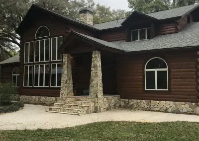 Dark-stained log home with stone entry columns and arched windows
