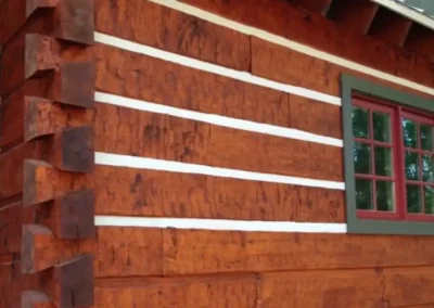 Dovetail log corner with white chinking lines between red-stained logs