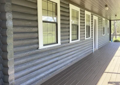 Gray-painted log wall along a long covered porch