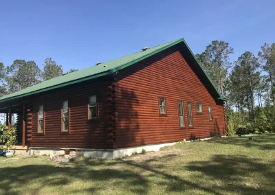 Log home with a deep red stain and green metal roof