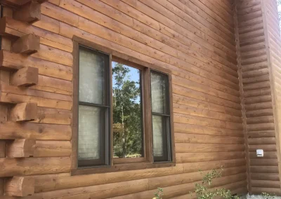 Freshly stained log wall with a window and corner log ends