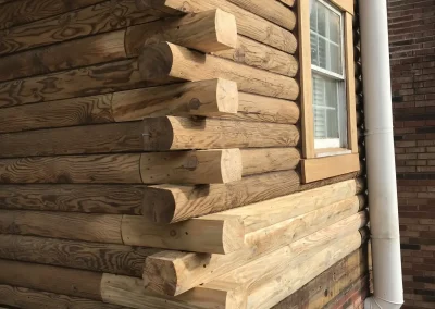 Weathered saddle-notched log corner beside a window